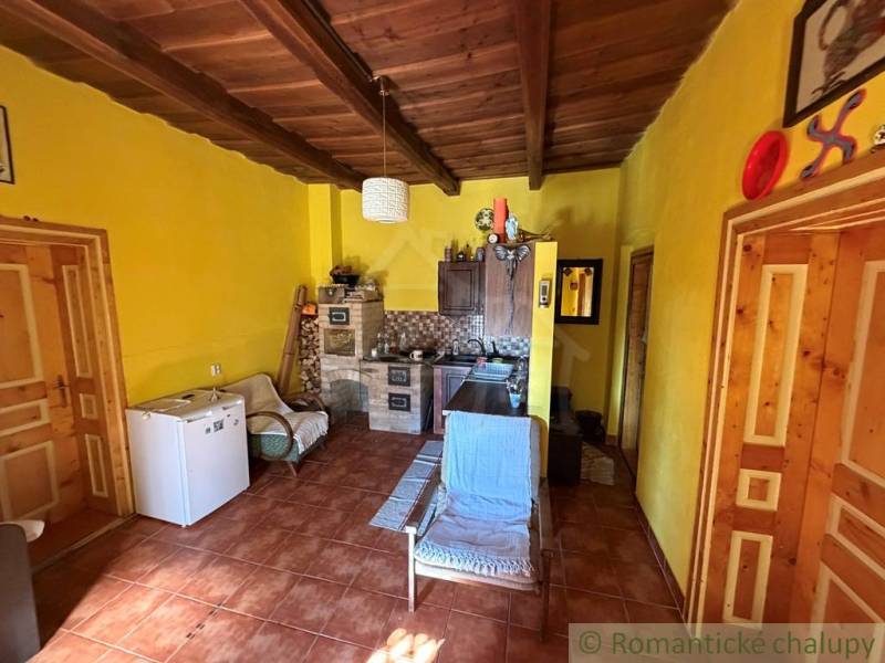 Interiér rodinného domu s dřevěným stropem a žlutými stěnami.