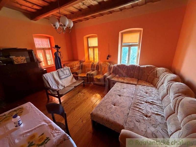 Obývací pokoj v rodinném domě s velkou pohovkou a podlahou s dřevěným dekorem.