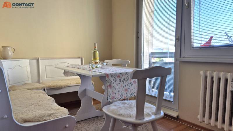 Jídelní kout v 2-pokojovém bytě s podlahou v dřevěném dekoru.