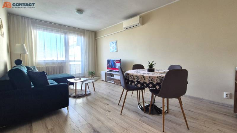 Obývací pokoj v 2-pokojovém bytě s podlahou s dřevěným dekorem, pohovkou a jídelním stolem.