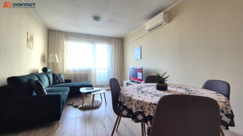 Obývací pokoj v 2-pokojovém bytě s pohovkou, jídelním stolem a podlahou s dřevěným dekorem.