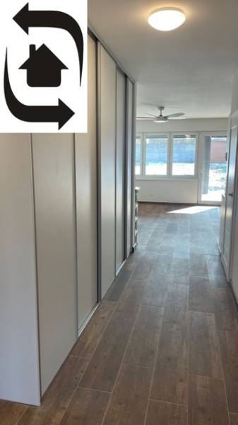 Chodba v rodinném domě s podlahou s dřevěným dekorem, velká okna, vestavěné skříně.