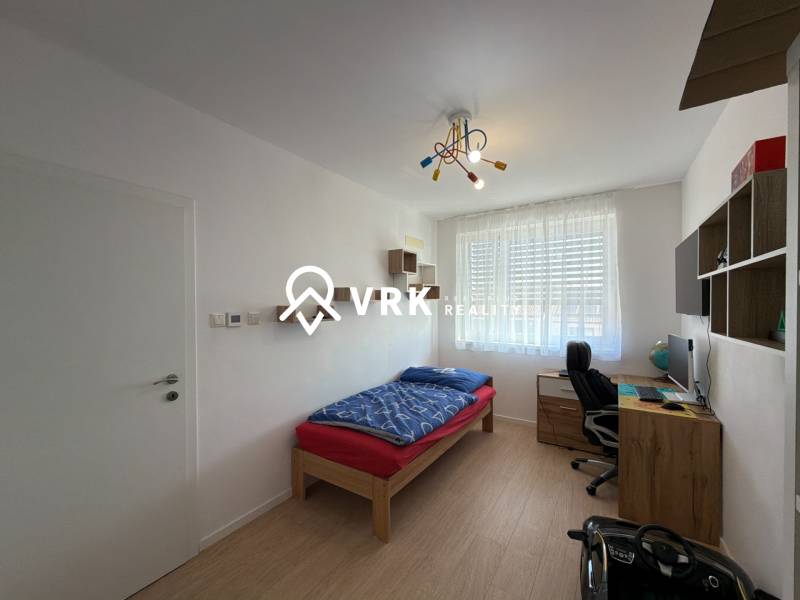 Dětský pokoj ve 3-pokojovém bytě s podlahou s dřevěným dekorem, psacím stolem, postelí.