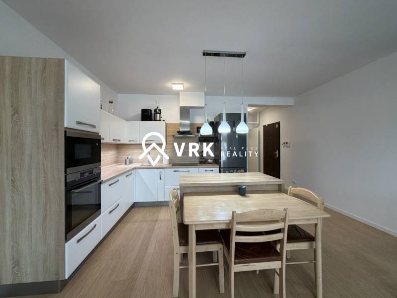 Kuchyně v 3-pokojovém bytě s podlahou s dřevěným dekorem a jídelním stolem.