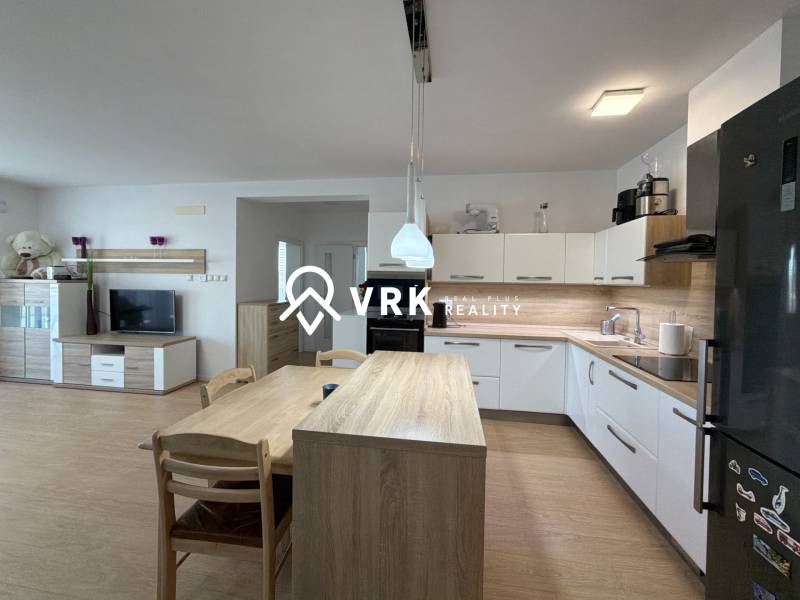 Kuchyně v 3-pokojovém bytě, podlaha s dřevěným dekorem, moderní spotřebiče a jídelní stůl.