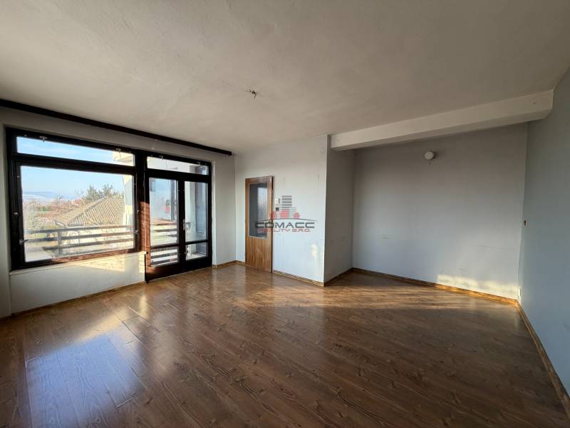 Pokoj v rodinném domě s podlahou s dřevěným dekorem, velkým oknem a dveřmi.