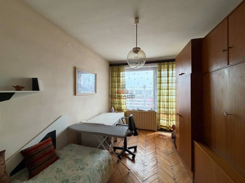 Pokoj v rodinném domě s podlahou s dřevěným dekorem, gaučem a velkou skříní.