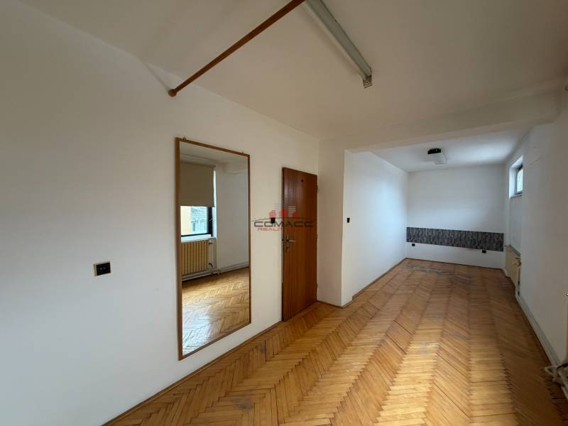 Pokoj v rodinném domě s podlahou s dřevěným dekorem, zrcadlem a oknem.