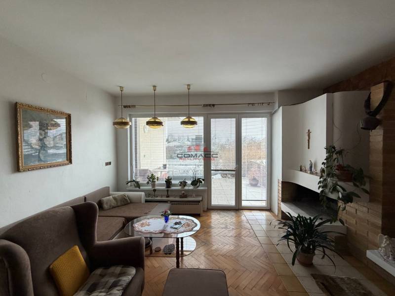 Obývací pokoj v rodinném domě s krbem, sedačkou a podlahou s dřevěným dekorem.