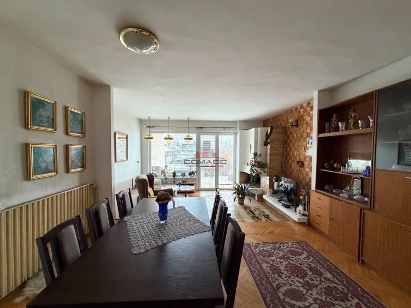 Obývací pokoj v rodinném domě s podlahou s dřevěným dekorem, jídelním stolem a krbem.