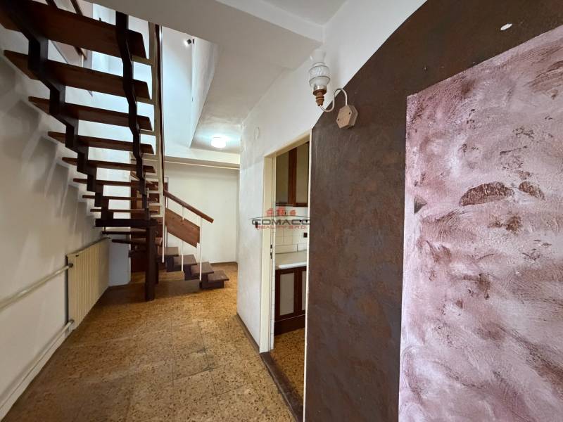 Chodba s otevřenými schody v rodinném domě, podlaha s dřevěným dekorem.