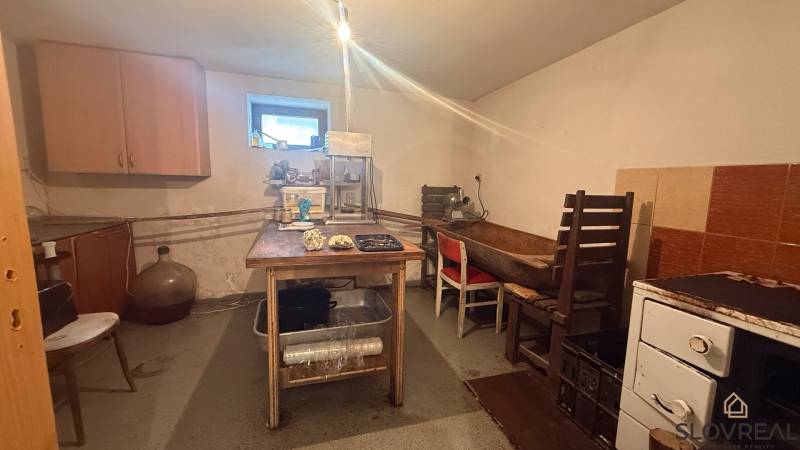 Kuchyně v rodinném domě s jednoduchým nábytkem a zařízením na zpracování potravin.