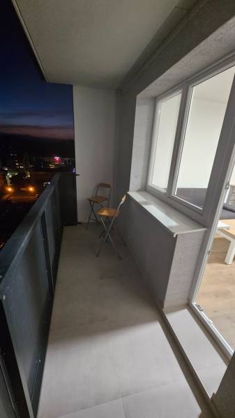 Balkon garsonky v Pod Hájem, Dubnica nad Váhom, se sklápěcí židlí a podlahou z dlaždic.
