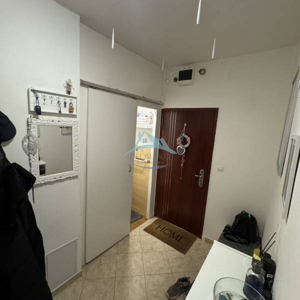 Předsíň 3-pokojového bytu s věšáky, zrcadlem a vchodovými dveřmi.