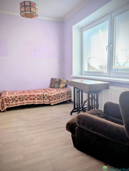 Pokoj v rodinném domě s rozkládací pohovkou a křeslem, podlaha s dřevěným dekorem.