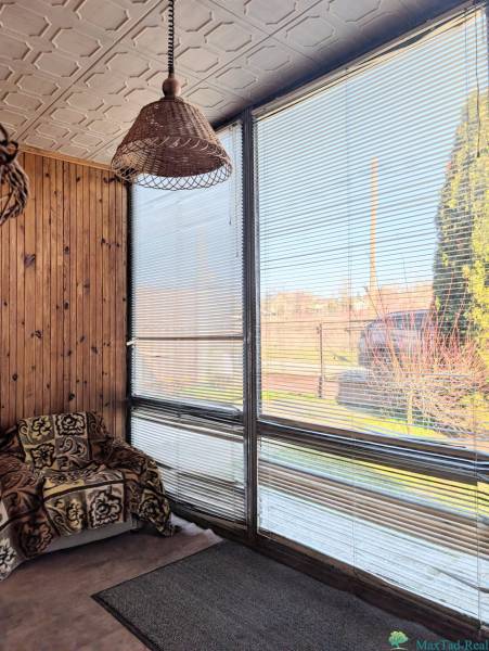 Rodinný dům s ratanovou lampou, křeslem s dekou a okny se žaluziemi.