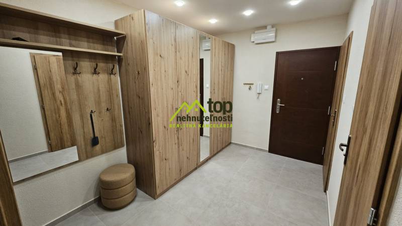 Chodba v 2-pokojovém bytě s nábytkem s dřevěným dekorem a vestavěným zrcadlem.