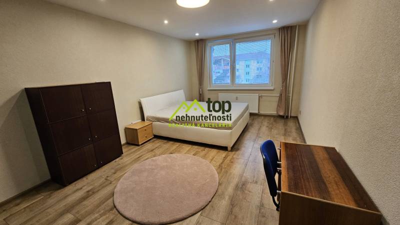 Světlý pokoj v 2-pokojovém bytě s postelí a nábytkem, podlaha s dřevěným dekorem.