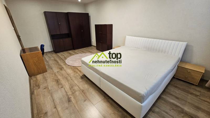 Ložnice v 2-pokojovém bytě s postelí, skříní a podlahou s dřevěným dekorem.