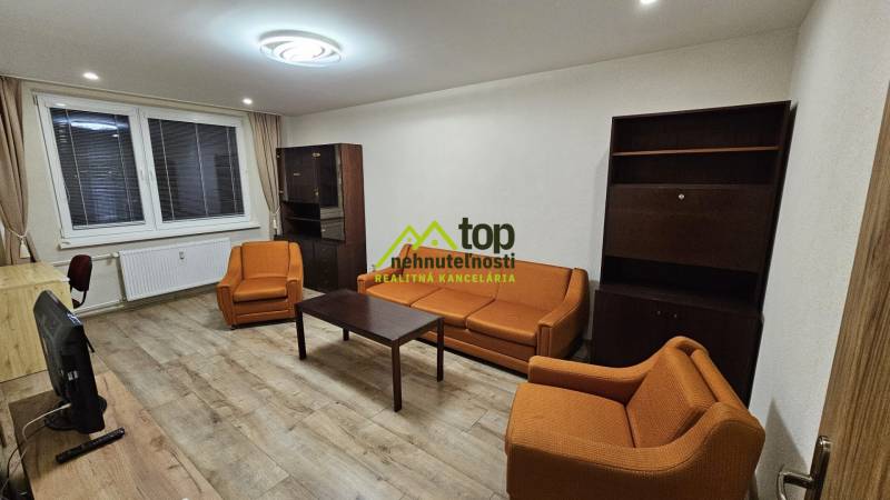 Obývací pokoj v 2-pokojovém bytě s oranžovými sedačkami a podlahou s dřevěným dekorem.