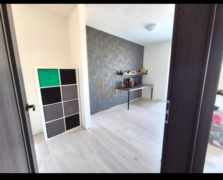 Pokoj v 3-pokojovém bytě s podlahou s dřevěným dekorem a dekorativní stěnou.