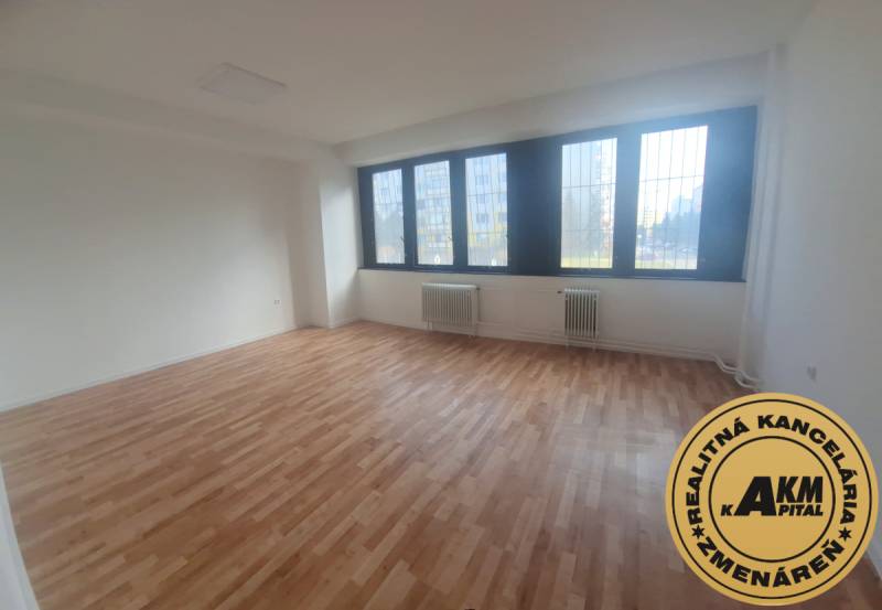 Interiér kanceláře s podlahou s dřevěným dekorem a velkými okny.