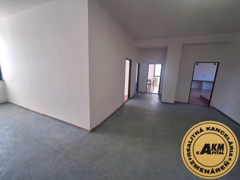 Volný prostor kanceláří s bílými stěnami a linoleovou podlahou.