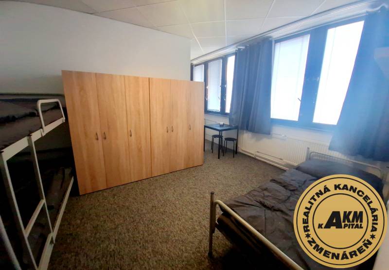 Nábytek v interiéru budovy s postelemi, skříní a stolem na koberci.