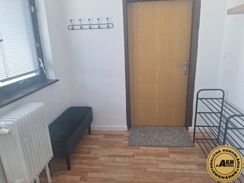 V Budově s podlahou s dřevěným dekorem je lavička, radiátor a věšák na stěně.