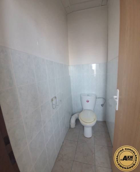 Toaleta v budově s keramickými obklady a dlažbou.