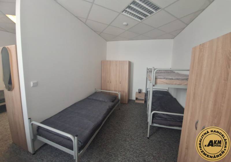 Interiér budovy s postelemi a skříněmi, podlaha s dřevěným dekorem.