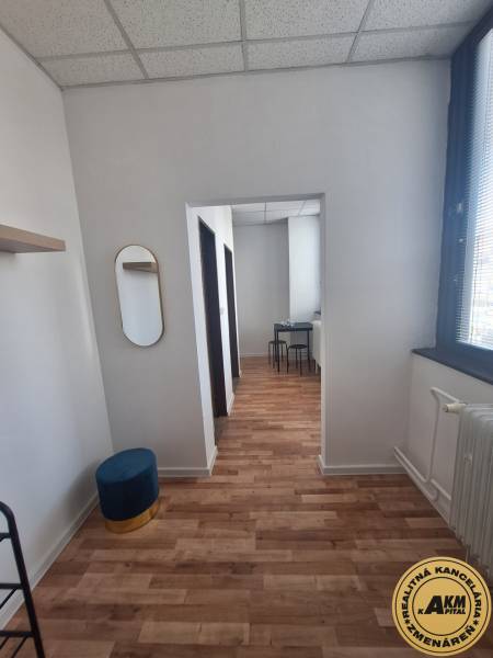 Interiér budovy s podlahou s dřevěným dekorem, židle, zrcadlo, bílý strop.