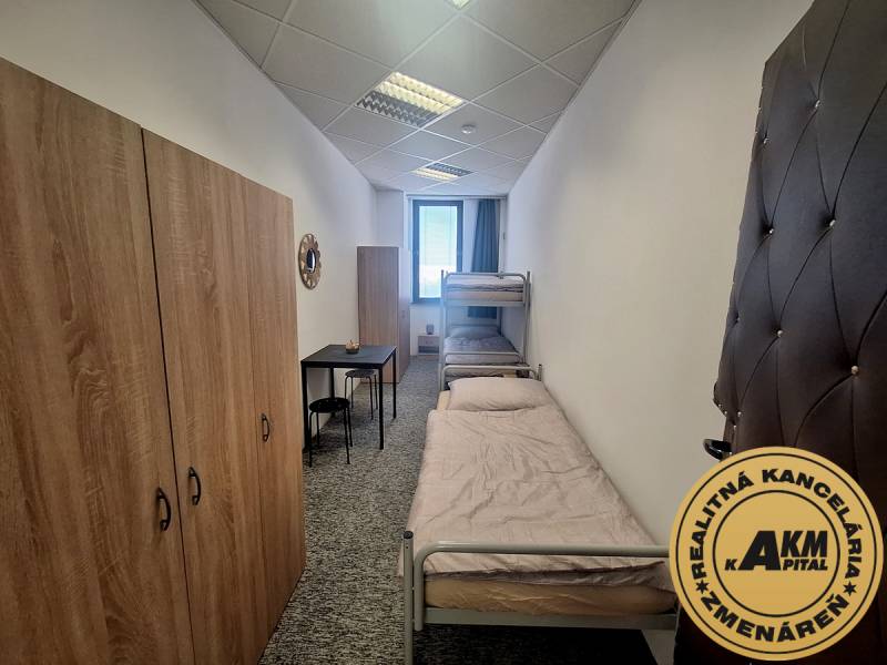 Interiér budovy s dvěma postelemi, skříněmi a malým stolkem na pokoji.