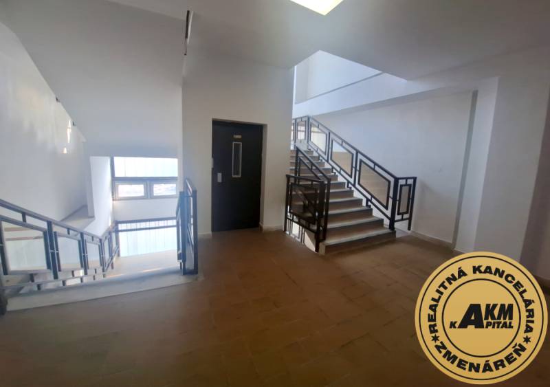 Interiér budovy se schodištěm a výtahem, podlaha s dřevěným dekorem.