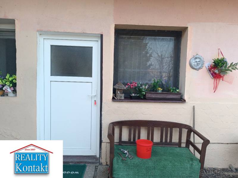 Vstup do 1-pokojového bytu s lavičkou a květinovou výzdobou.