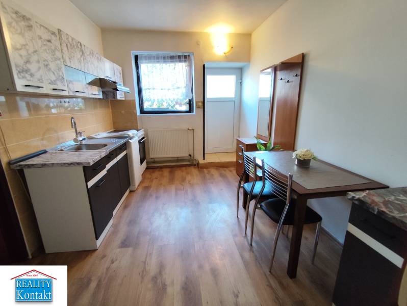 Kuchyně v 1-pokojovém bytě s podlahou s dřevěným dekorem a jídelním stolem.