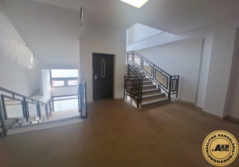 Schodiště v obchodních prostorách s okny a podlahou s dřevěným dekorem.