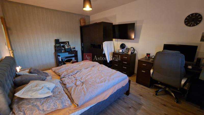 Ložnice v 3pokojovém bytě s pohodlnou postelí, pracovním stolem a podlahou s dřevěným dekorem.