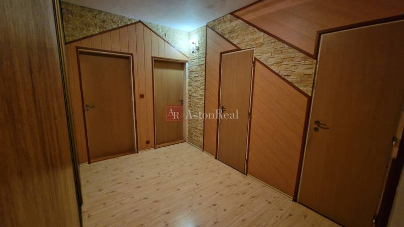 Chodba se třemi dveřmi a podlahou s dřevěným dekorem ve 3-pokojovém bytě.