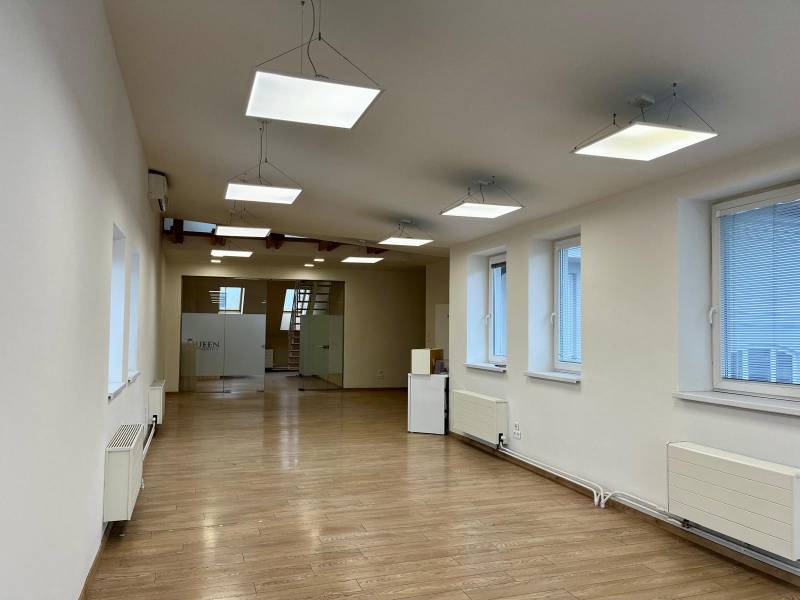 Kanceláře s podlahou s dřevěným dekorem, závěsnými svítidly a prosklenými dveřmi.