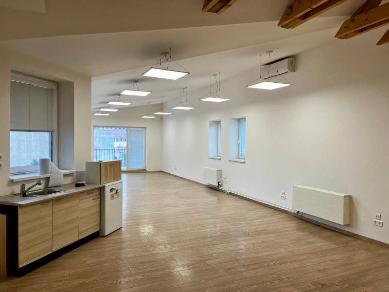 Kanceláře s podlahou s dřevěným dekorem a kuchyňským koutem, stropní osvětlení.