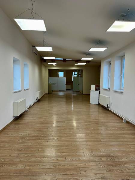 Interiér kanceláří s podlahou s dřevěným dekorem a závěsnými světly.