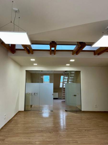 Interiér kanceláře s podlahou s dřevěným dekorem a skleněnými dveřmi.