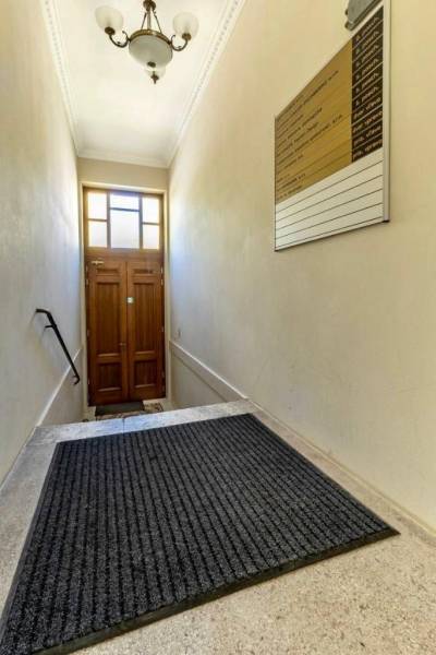 Úzké schodiště s žebříkem a lampou vede ke dřevěným dveřím. Kanceláře.