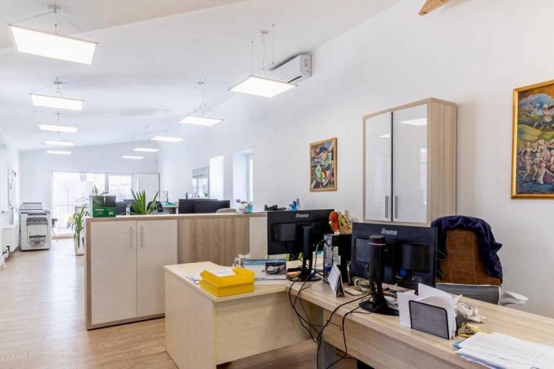 Kanceláře s podlahou s dřevěným dekorem, pracovními stoly a skladovými skříňkami.