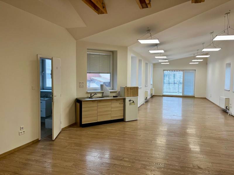 Kanceláře s podlahou s dřevěným dekorem, velkými okny a kuchyňským koutem.