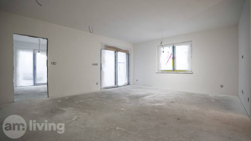 Pokoj v rodinném domě s nedokončenými podlahami a stěnami, bez zařízení.