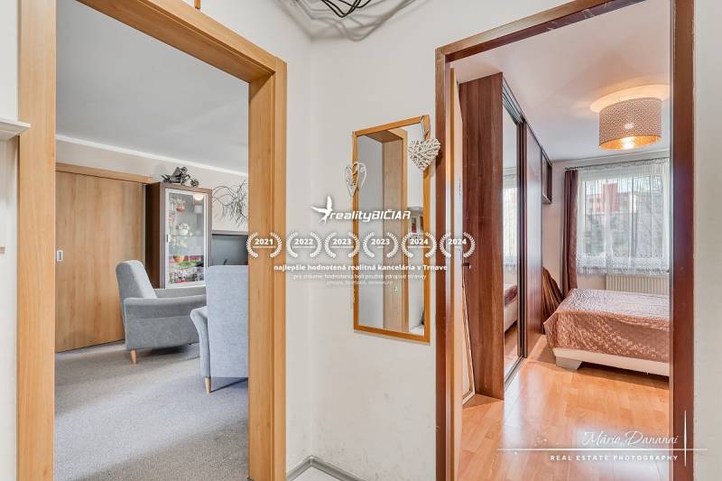 Interiér 4-pokojového bytu s podlahou s dřevěným dekorem, nábytkem a zrcadlem.