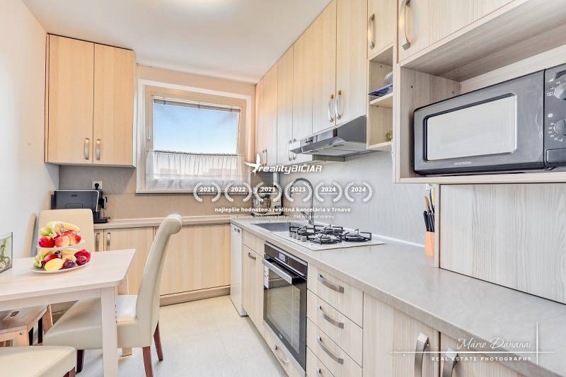 Kuchyně ve 4-pokojovém bytě s ovocem na stole a vestavěnými spotřebiči.