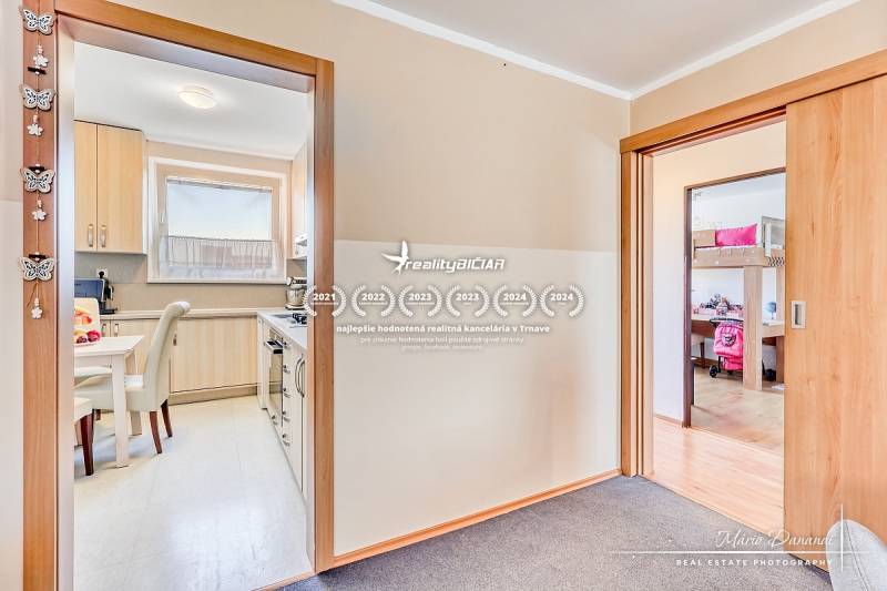 Kuchyně a dětský pokoj ve 4-pokojovém bytě s podlahou s dřevěným dekorem.